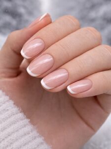 Minimal winter nails with sheer pink base and thin white micro French tips, short oval nails, classic minimal manicure in San Diego