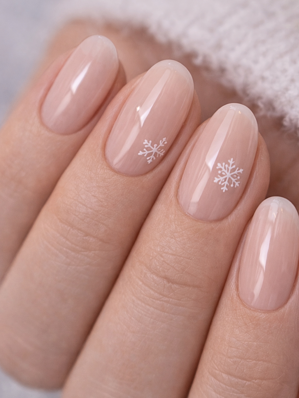 Minimal winter nails with glossy sheer nude pink and tiny white snowflake accents, short almond shape, San Diego nail salon