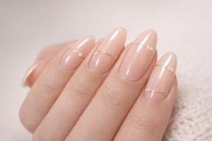 Minimal nude almond nails with delicate gold lines and pearl accents March Nail Trends at Blissful Beauty Nail Lounge San Diego