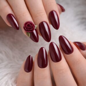 Glossy burgundy almond nails with 3D rose accent and white and gold swirl details, International Women’s Day Nails at Blissful Beauty Nail Lounge